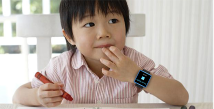Color photo of a child holding a crayon in his right hand and wearing a smartwatch on his left hand.
